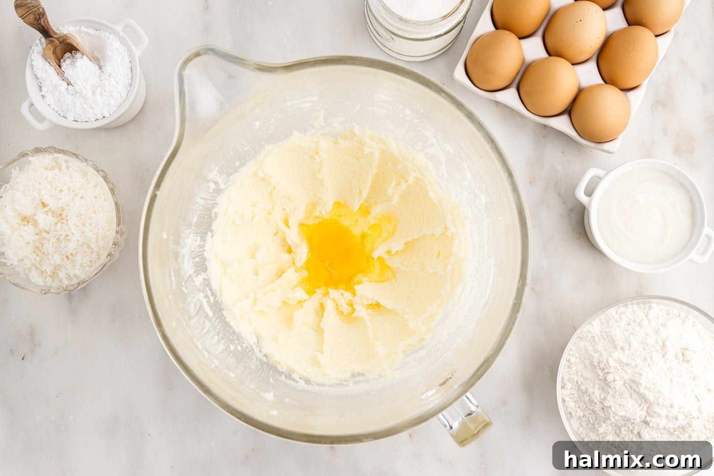 Eggs being gradually added to the creamed butter and sugar mixture in a mixing bowl, beaten until fully incorporated and smooth.