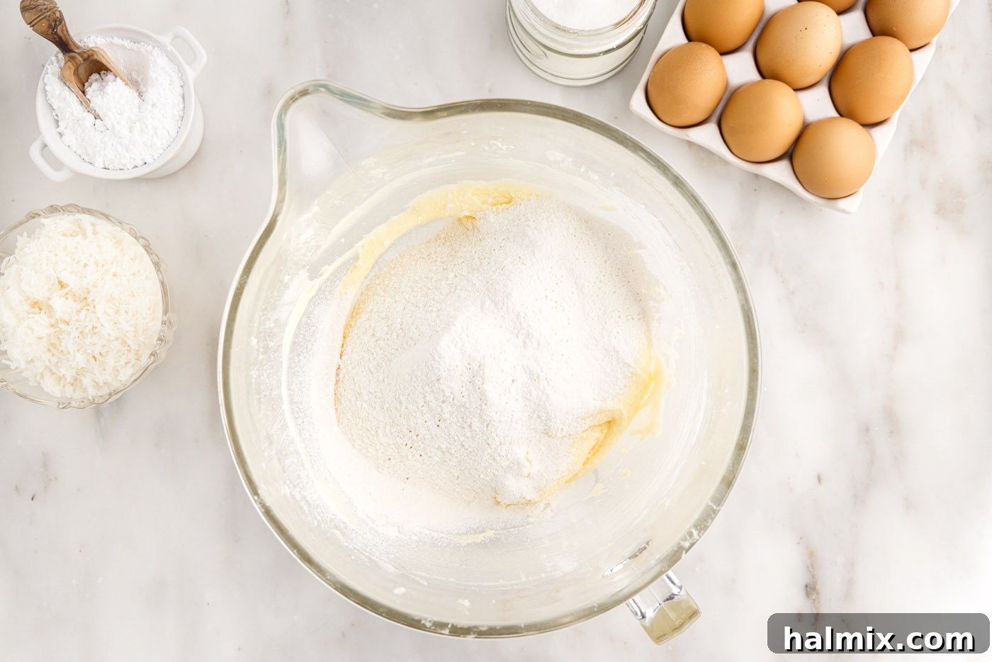 Dry ingredients (flour, baking powder, salt) being added to the wet cake batter mixture, ready for gentle combining.