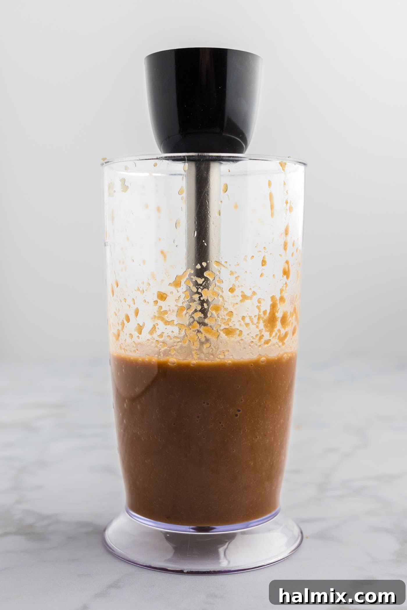 Immersion blender actively mixing the bulgogi marinade to a smooth consistency in a clear container.