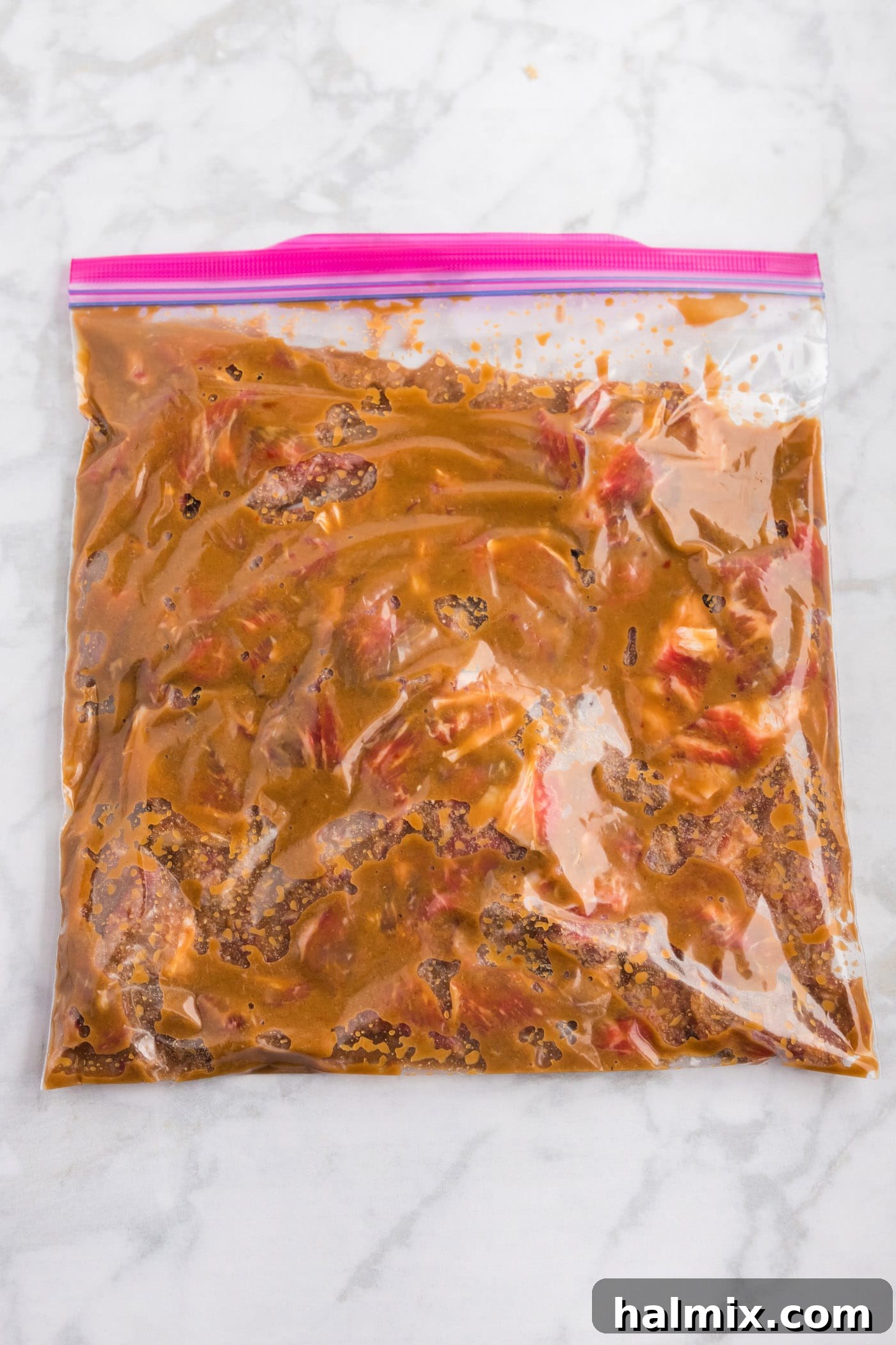 Marinated ribeye steak strips soaking in a large zip-top bag, ready for cooking.