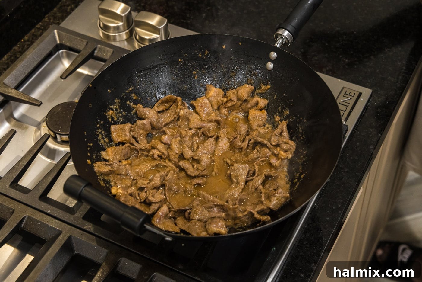Thin strips of marinated beef being added to a hot wok, ready for stir-frying.