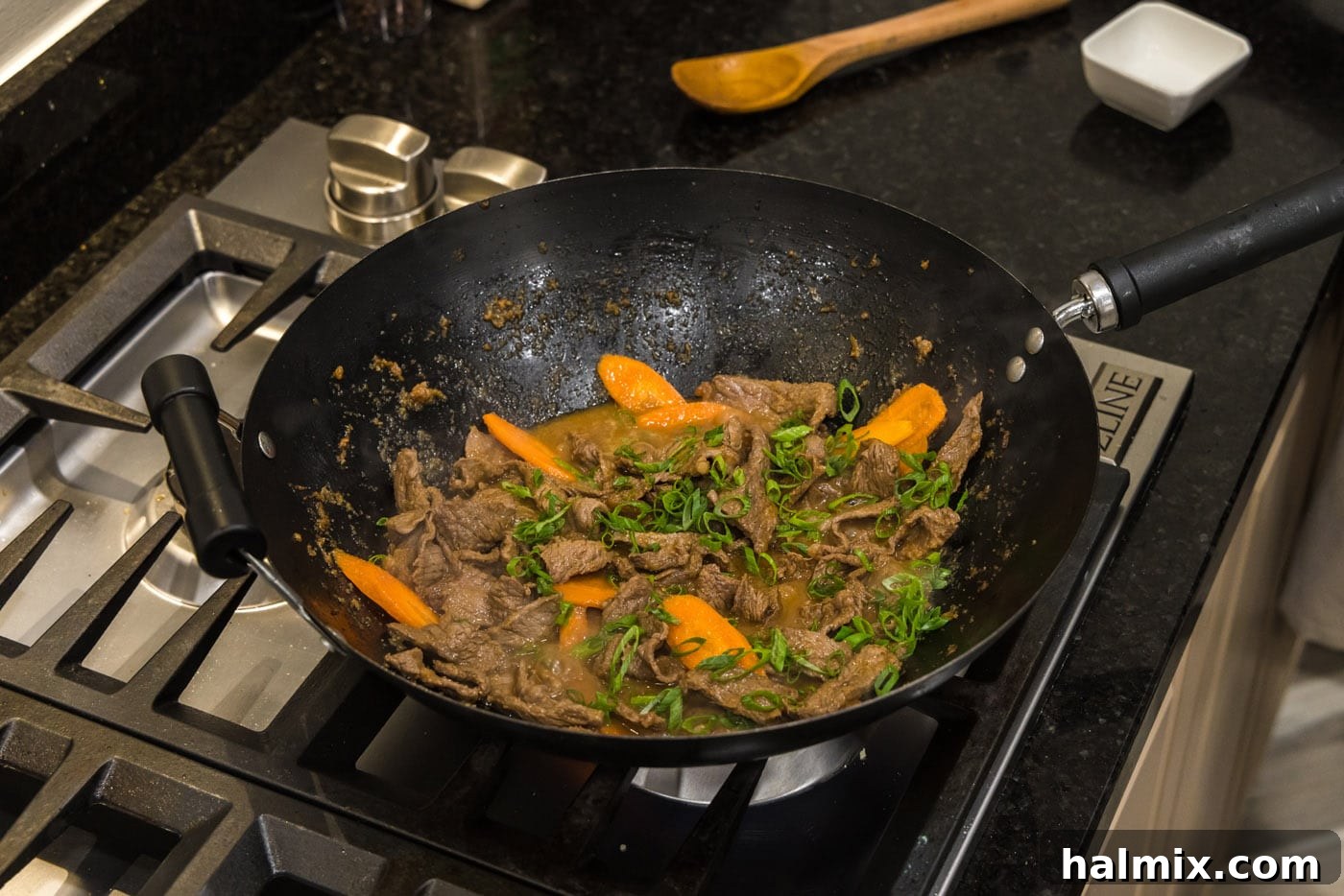 Beef, sliced carrots, and green onions combining and stir-frying in a wok.