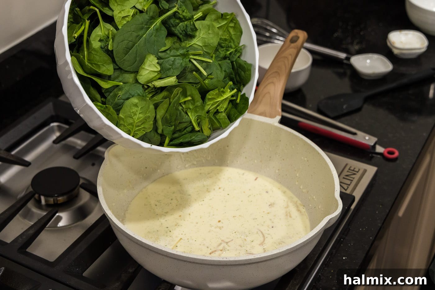 adding spinach to skillet with heavy cream mixture