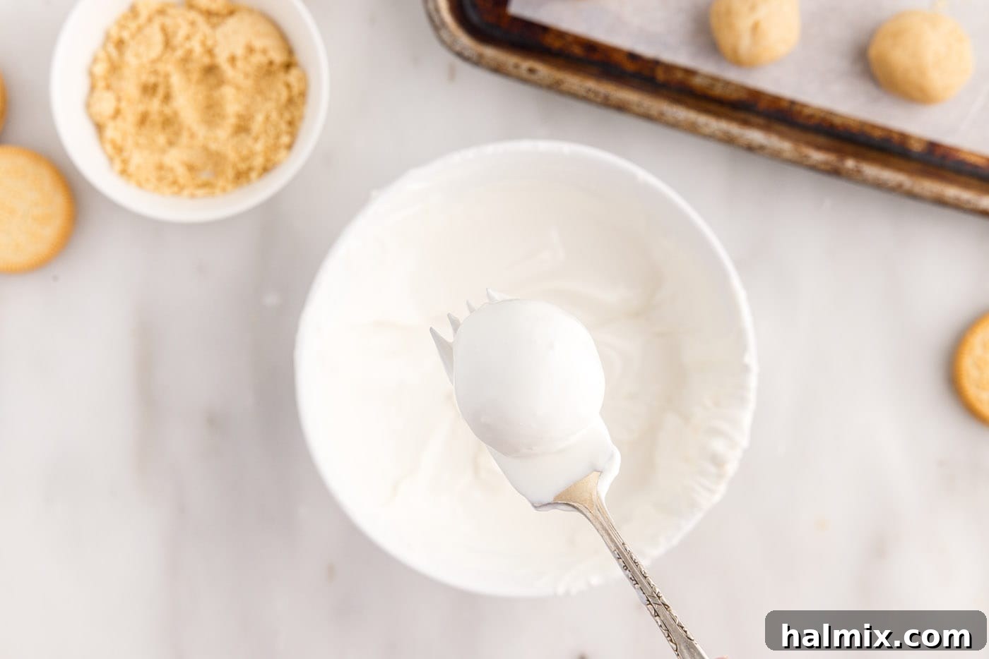 dipping Oreo truffles into white chocolate coating with a fork