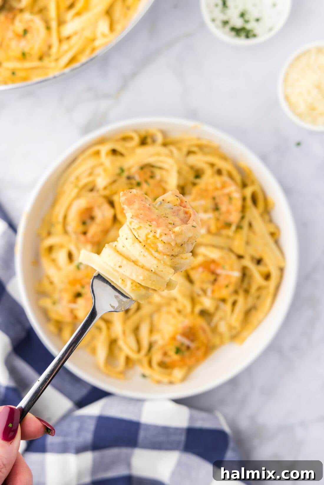Creamy Garlic Shrimp Alfredo 14 A fork twirling a perfect bite of Shrimp Alfredo, showcasing the tender shrimp, creamy sauce, and fettuccine noodles, held above a rustic bowl of the finished dish.
