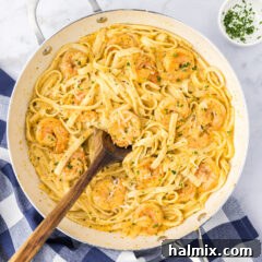 Creamy Garlic Shrimp Alfredo 15 A close-up view of Shrimp Alfredo in a cast-iron skillet, with a serving spoon nestled in the creamy pasta.