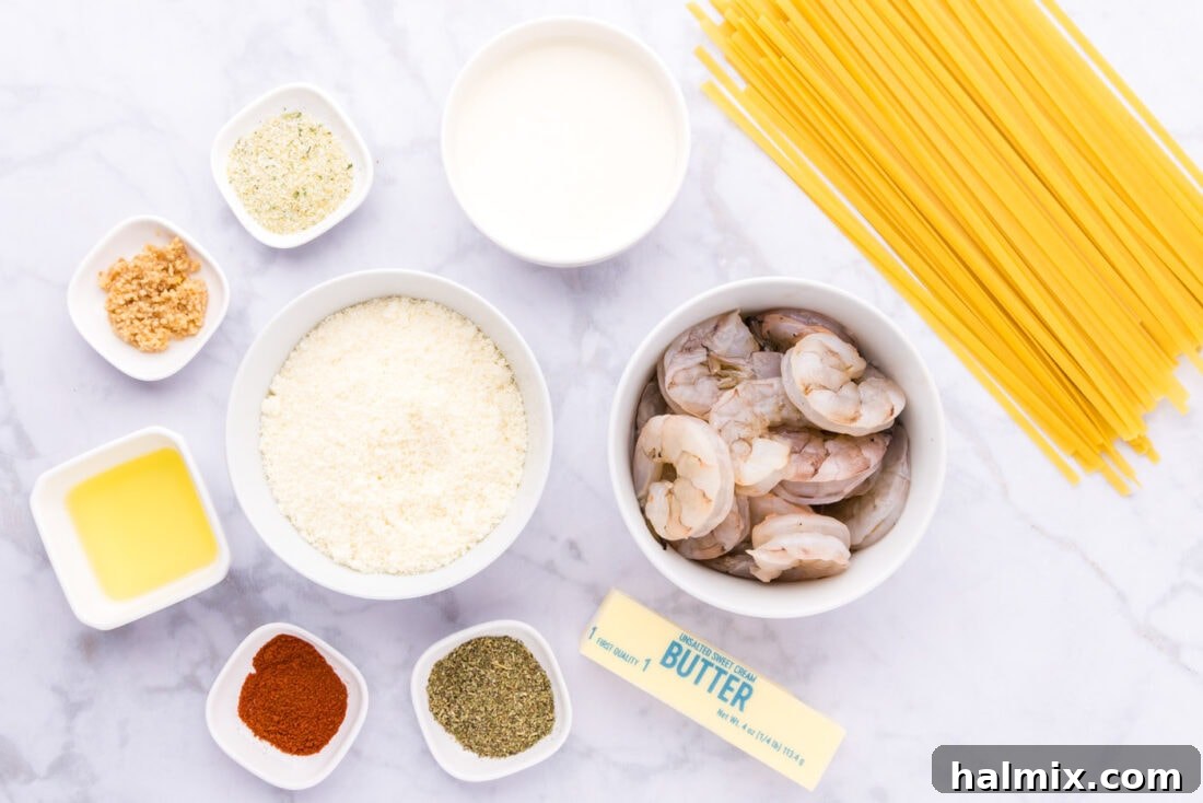 Creamy Garlic Shrimp Alfredo 4 An array of fresh ingredients laid out on a kitchen counter, including raw shrimp, a block of Parmesan cheese, heavy cream, butter, garlic, and fettuccine pasta, ready for making Shrimp Alfredo.
