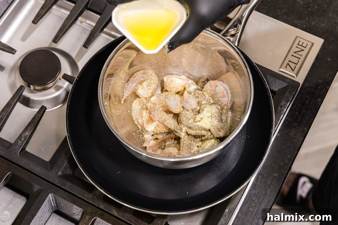 Creamy Garlic Shrimp Alfredo 5 Raw shrimp being tossed in a medium bowl with olive oil and garlic salt, preparing them for cooking.