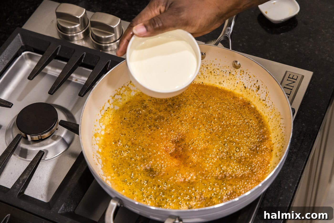 Creamy Garlic Shrimp Alfredo 9 Heavy cream being poured into the seasoned butter mixture in a skillet, creating the base for the Alfredo sauce.