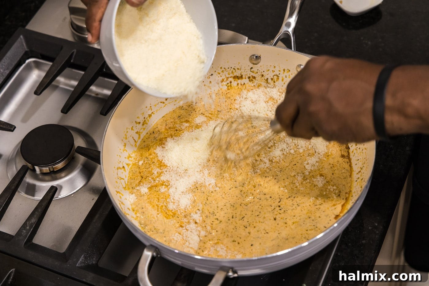 Creamy Garlic Shrimp Alfredo 10 Grated Parmesan cheese being sprinkled into the simmering cream sauce in a skillet, ready to be whisked in.