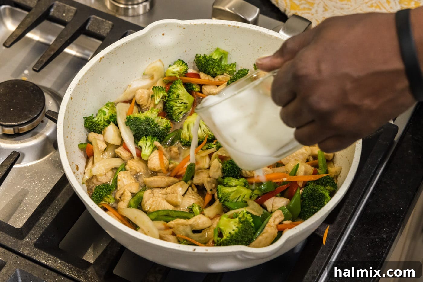 adding a cornstarch slurry to skillet of honey garlic chicken stir fry