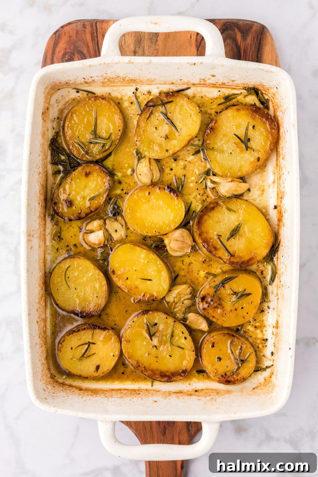 Baking dish of Melting Potatoes resting on a wooden platter