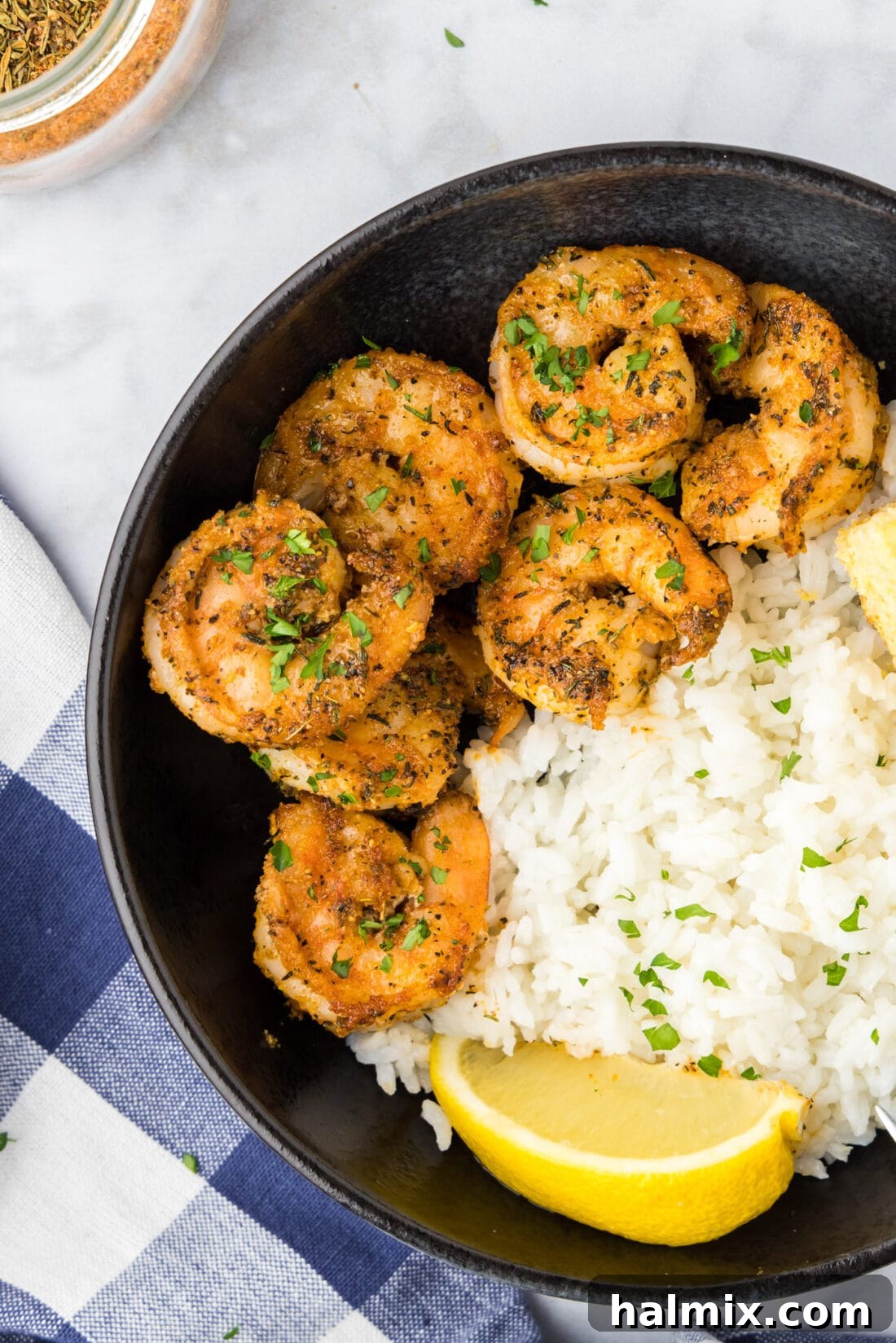 Close-up photo of a bowl filled with perfectly cooked Cajun shrimp, served over fluffy white rice, highlighting its rich color and inviting texture.