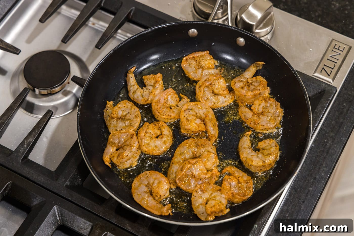 Cajun shrimp sizzling in a hot skillet with olive oil, showing the initial cooking phase.