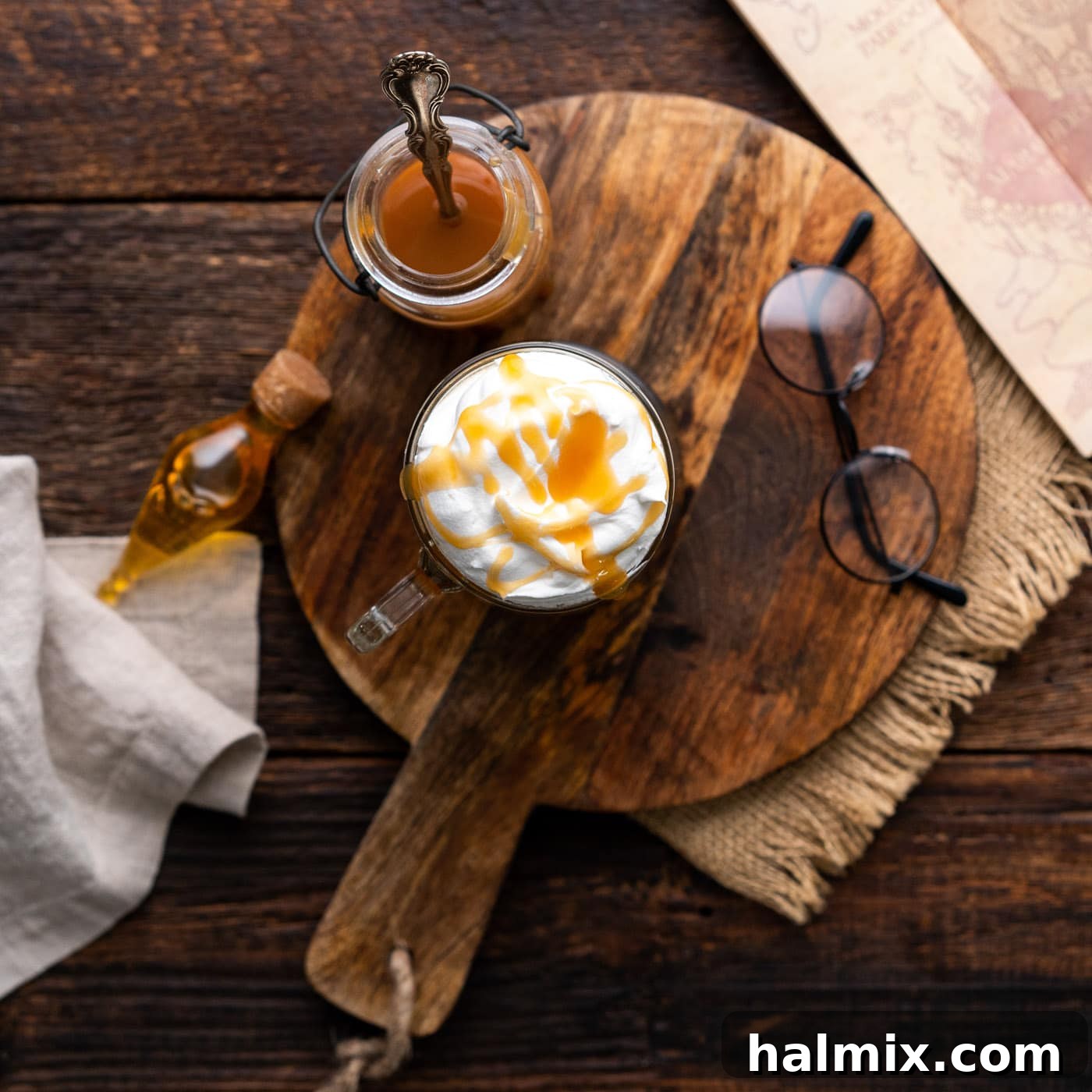 An overhead shot of two perfectly prepared Butterbeer glasses, topped with whipped cream and butterscotch drizzle, ready to be enjoyed.