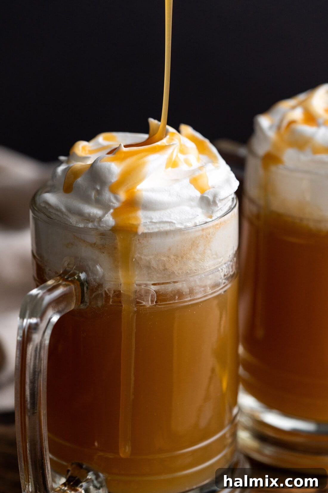 Rich butterscotch syrup being artfully drizzled over a freshly made glass of Butterbeer, enhancing its sweet appeal.