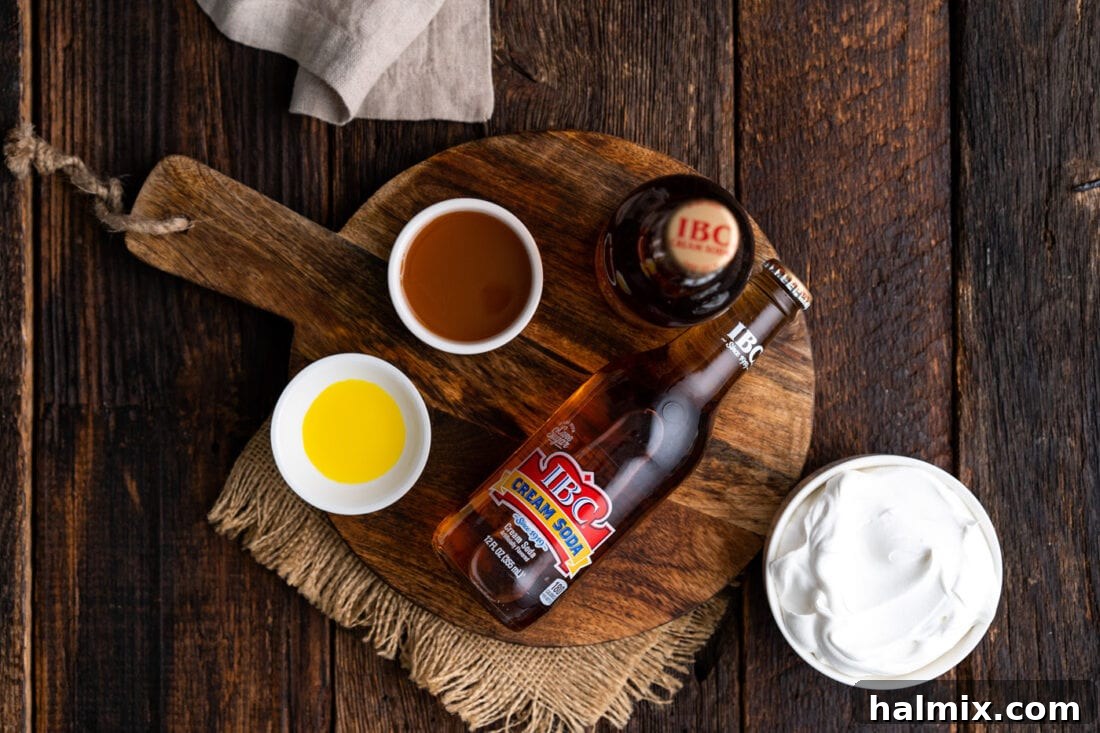A selection of ingredients laid out, including cream soda, butterscotch syrup, butter extract, and heavy cream for homemade Butterbeer.