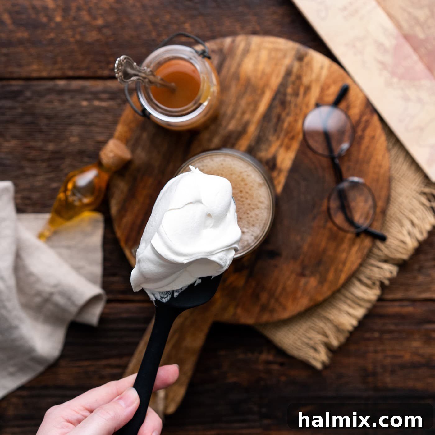 A dollop of fluffy whipped cream elegantly resting atop the golden butterbeer, creating a delightful contrast.