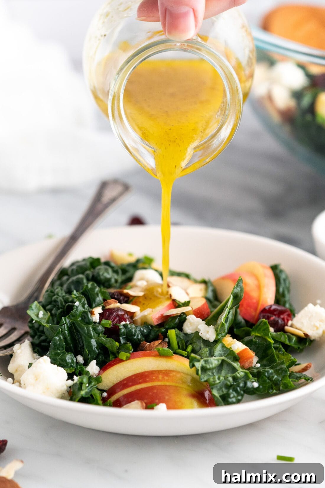 Lemon Salad Dressing being poured over a Kale Salad
