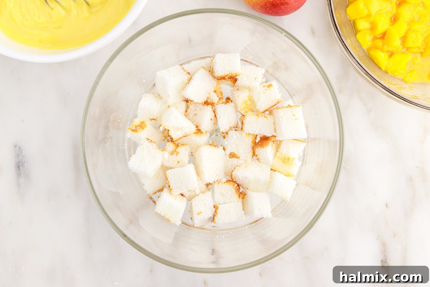 Cubed angel food cake forming the first layer in a trifle dish