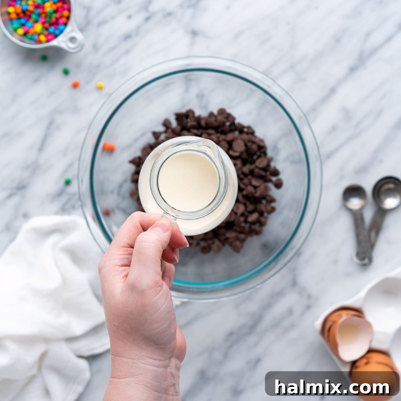 adding heavy whipping cream to chocolate chips in a bowl for ganache