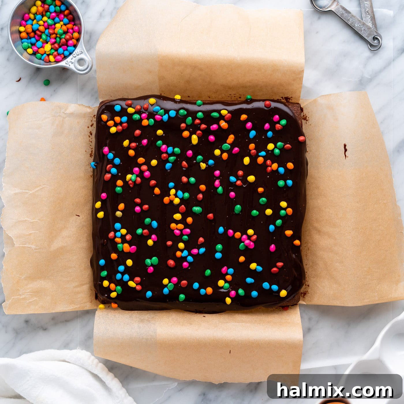 cosmic brownie sprinkles being added generously on top of the smooth ganache