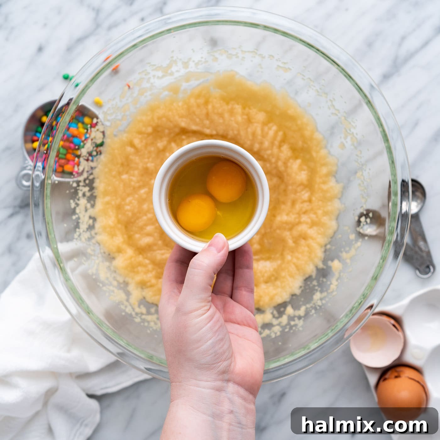 adding eggs to brownie wet batter in a mixing bowl