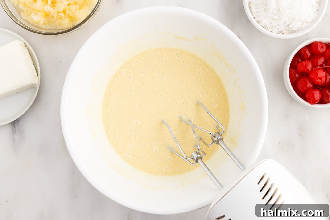 cake mix being blended in a bowl with a hand mixer, achieving a smooth consistency