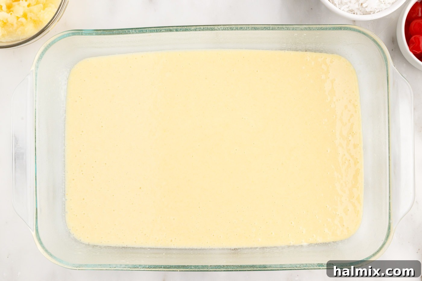 cake mix batter spread evenly in a glass baking dish, ready for the oven