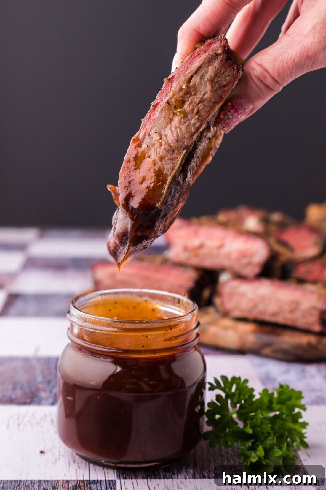 Fall-Off-The-Bone Smoked Beef Ribs 3 Smoked Beef Rib dipped in rich, tangy barbecue sauce, highlighting its succulent interior.