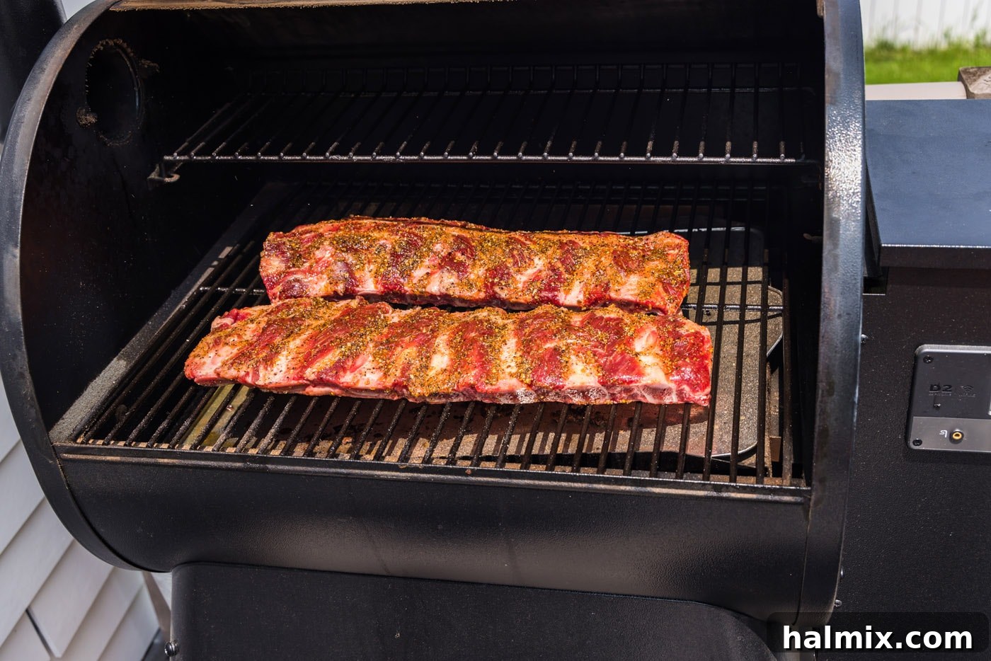 Fall-Off-The-Bone Smoked Beef Ribs 6 Beef ribs neatly arranged on the grates of a preheated smoker, beginning their slow cooking process.
