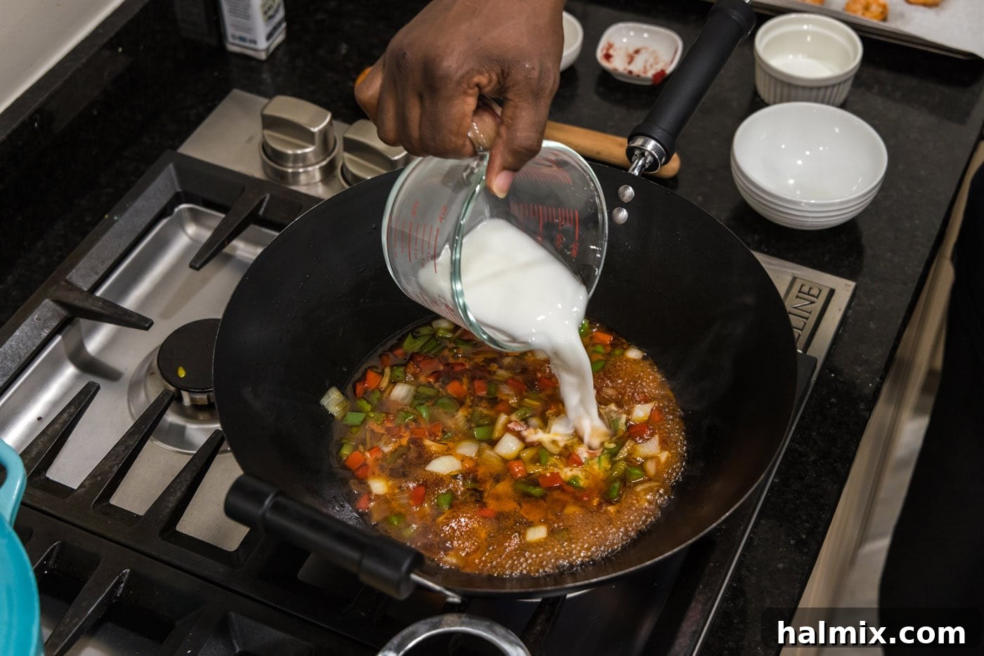 pouring cornstarch slurry into sweet and sour sauce in a skillet with vegetables