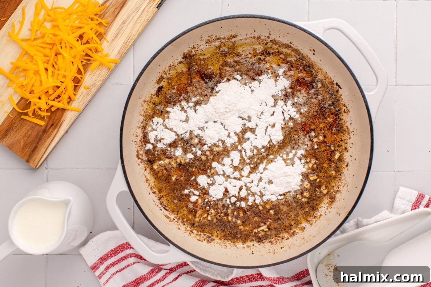 Flour being added to the skillet with butter and garlic, forming a roux.
