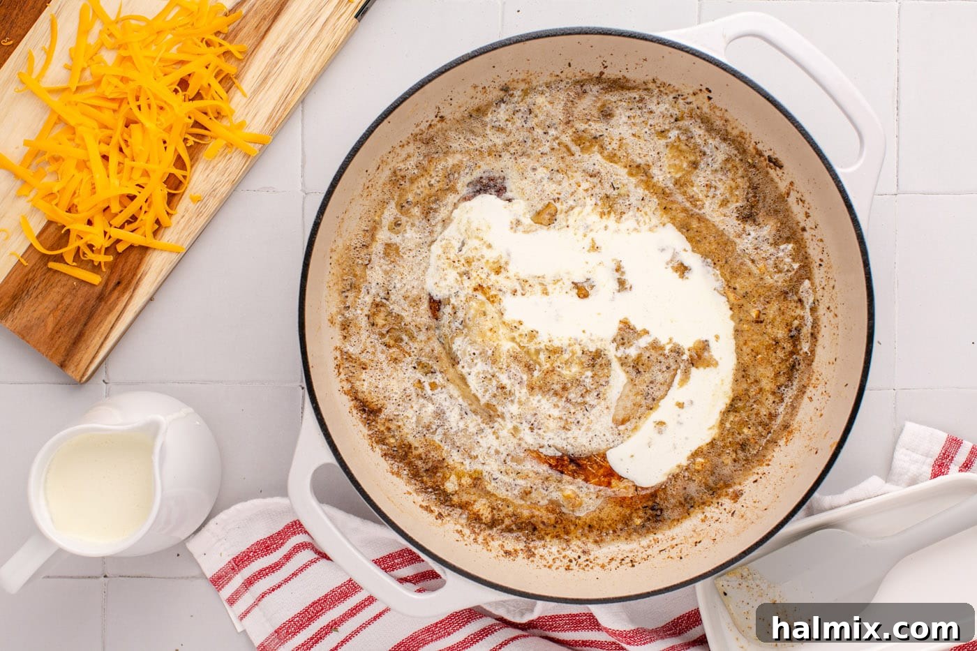 Heavy whipping cream being slowly added to the skillet with the butter-flour mixture, creating a creamy base.