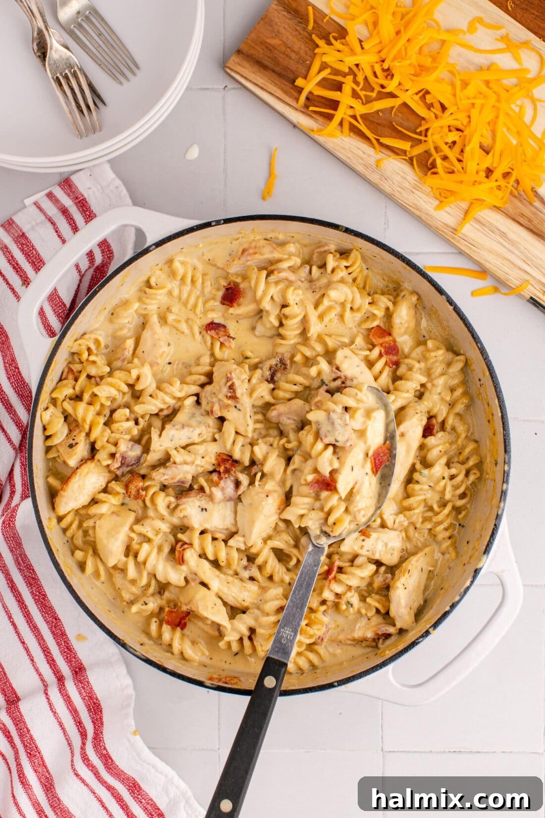 A large pot filled with Creamy Chicken Bacon Ranch Pasta, showcasing its inviting texture and warmth, with a serving spoon inside.