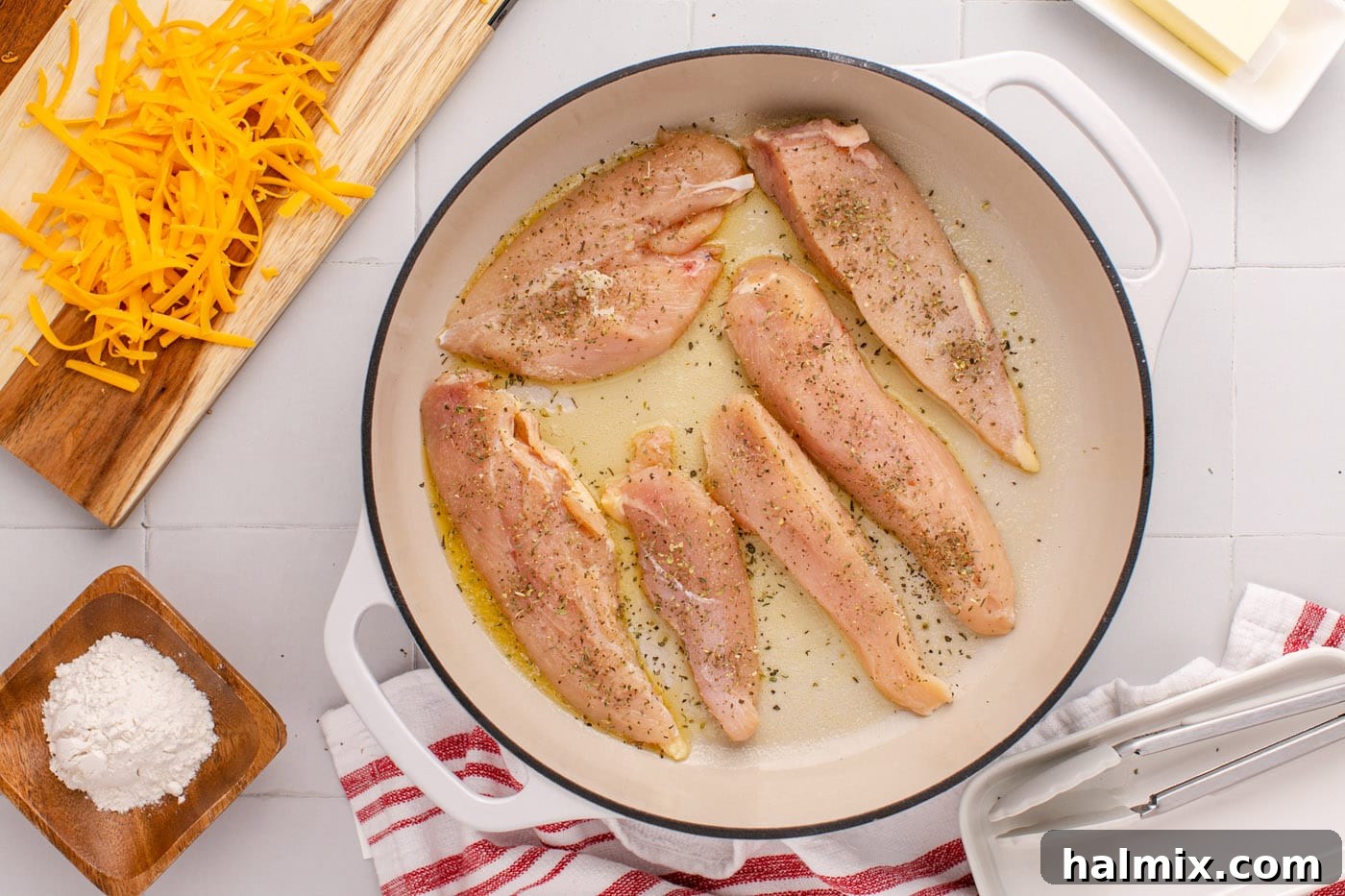 Chicken breasts cooking in melted butter in a large skillet, developing a golden crust.