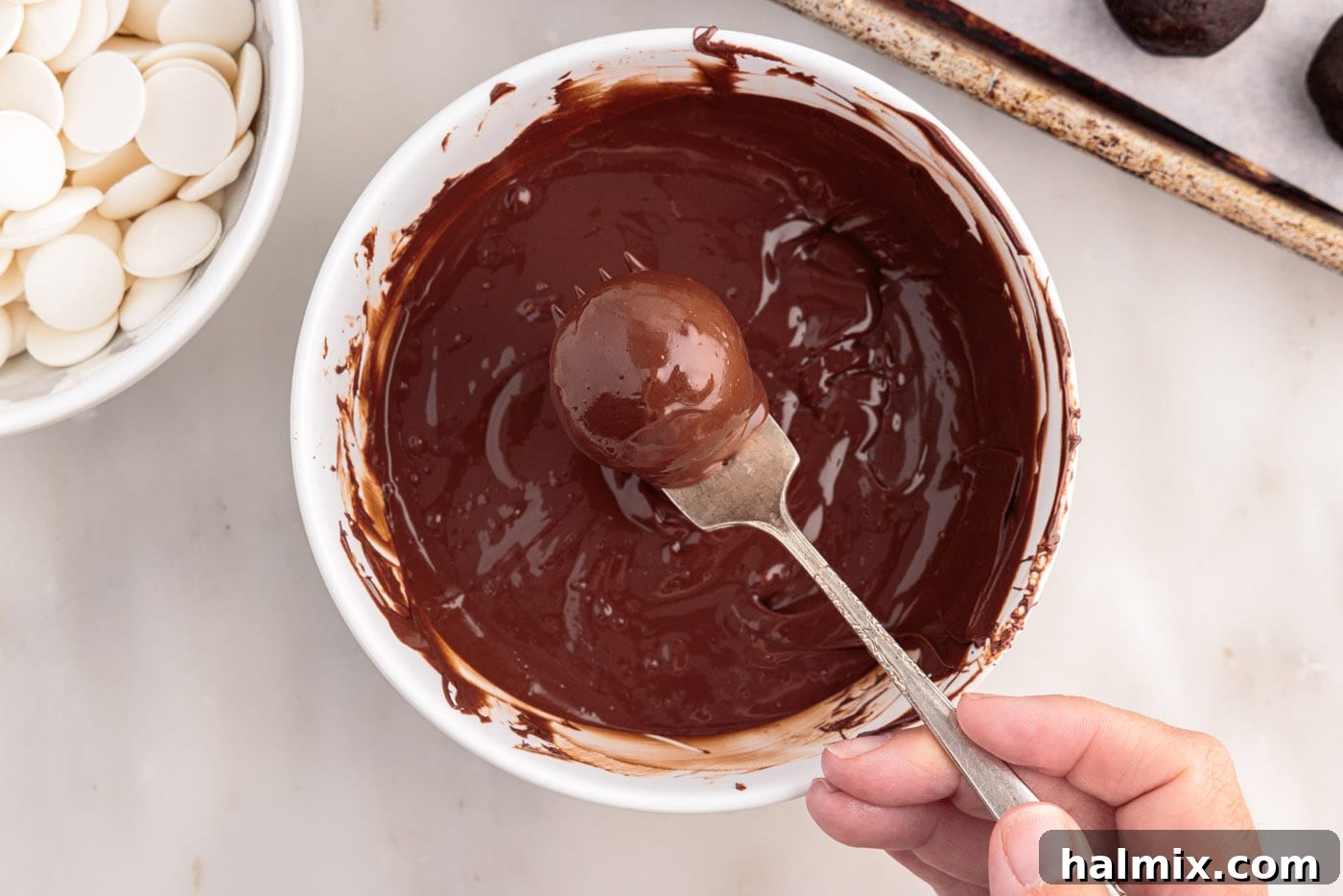 removing oreo truffles from chocolate with a fork, allowing excess to drip