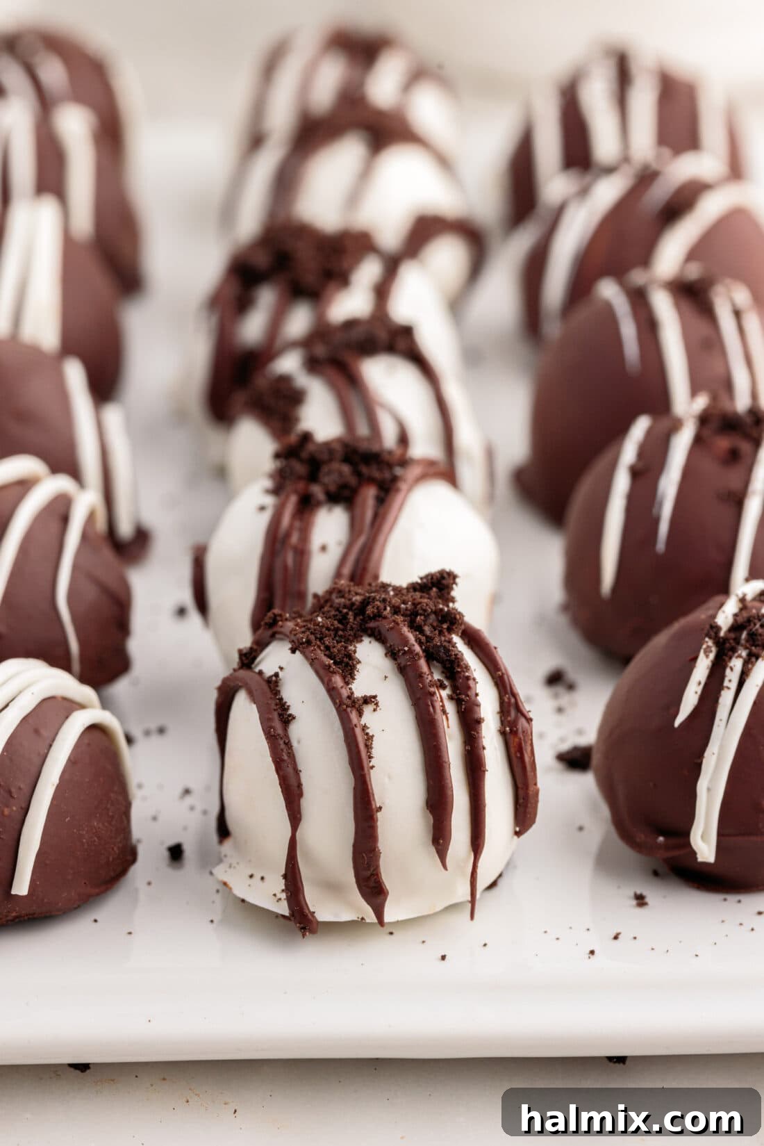 Oreo Truffles lined on on a tray with parchment paper, some coated in white chocolate, some in dark chocolate.