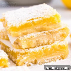 A stack of golden lemon bars dusted with powdered sugar, showcasing the beautiful layers of crust and filling, ready to be enjoyed.