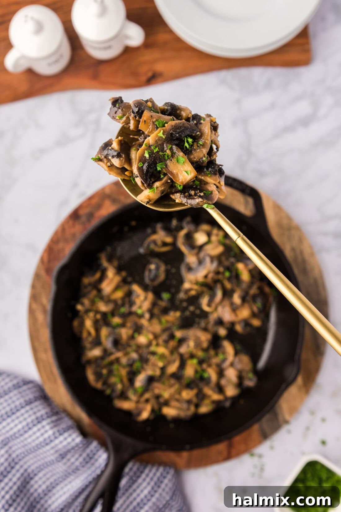 Spoonful of Sautéed Mushrooms held over a skillet, showcasing their rich color and texture.