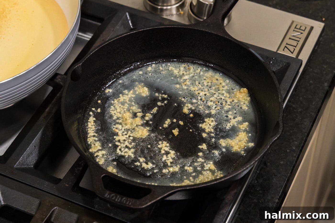 Minced garlic sizzling in melted butter in a hot skillet.