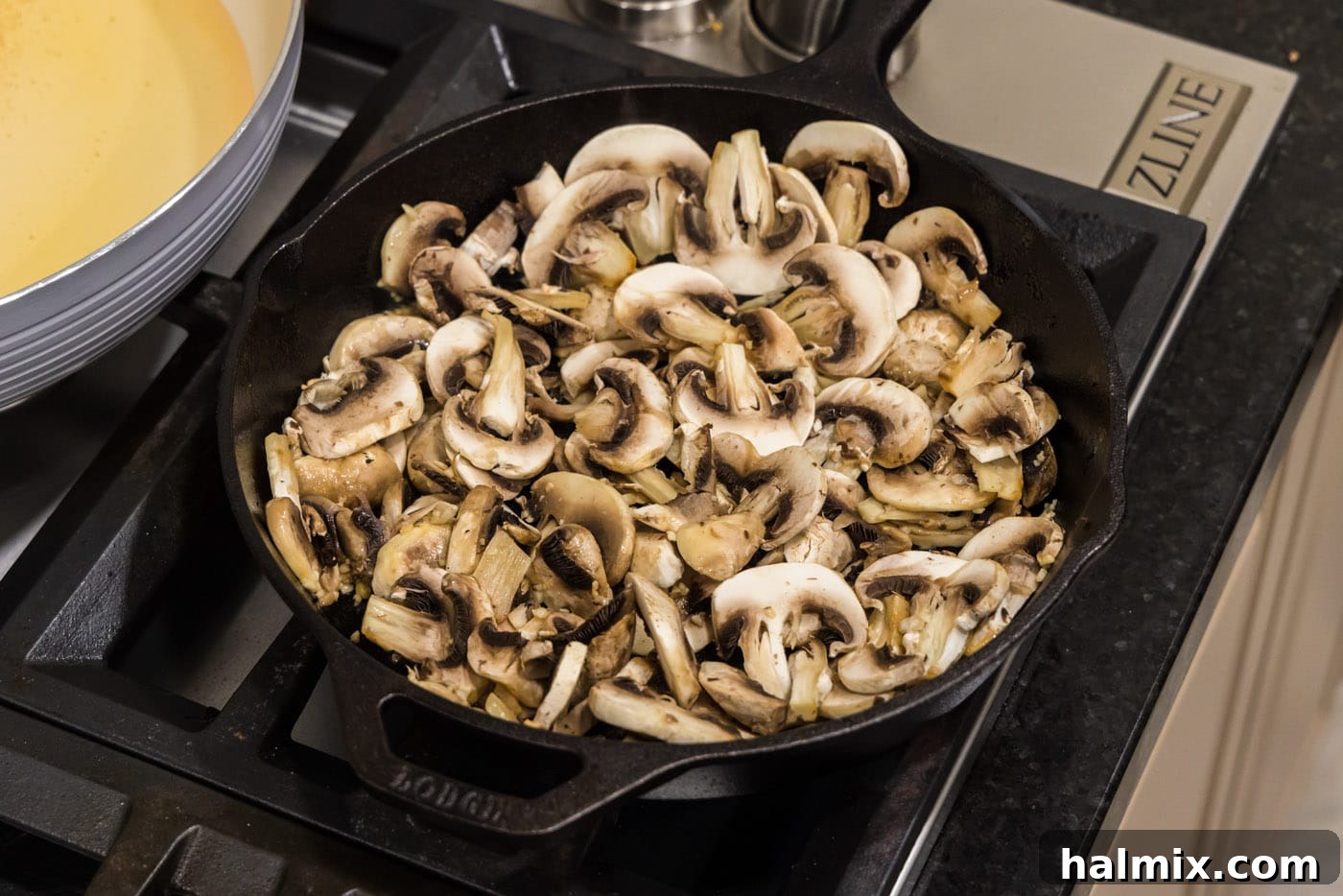Sliced mushrooms being added to the hot skillet with butter and garlic.