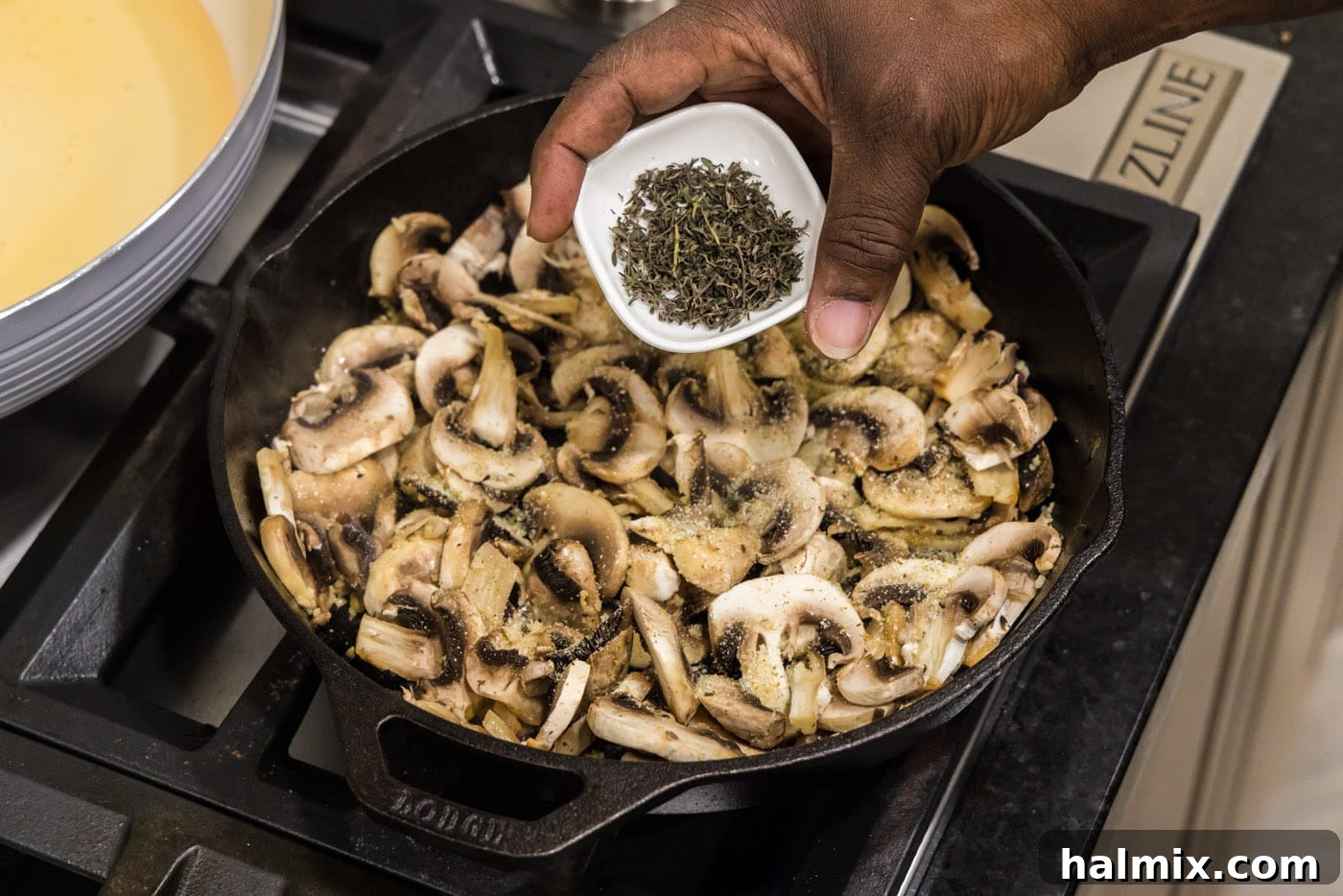 Fresh thyme leaves being sprinkled over the mushrooms in the skillet.