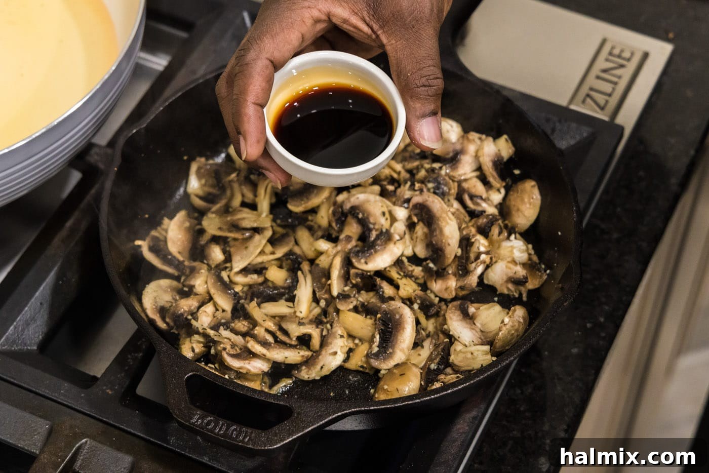 Soy sauce being stirred into the mushrooms and garlic in the skillet.