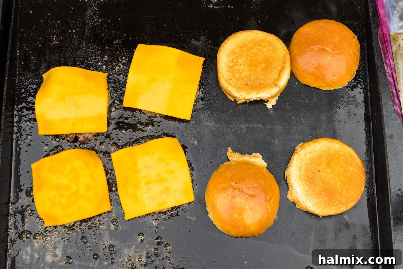 Cheese melting on top of burger patties on the griddle