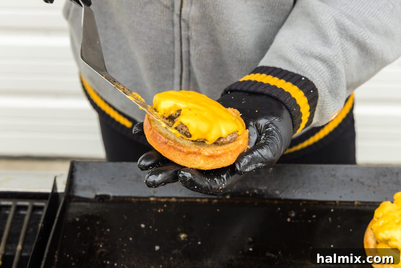 Adding a burger patty with melted cheese to a toasted bun