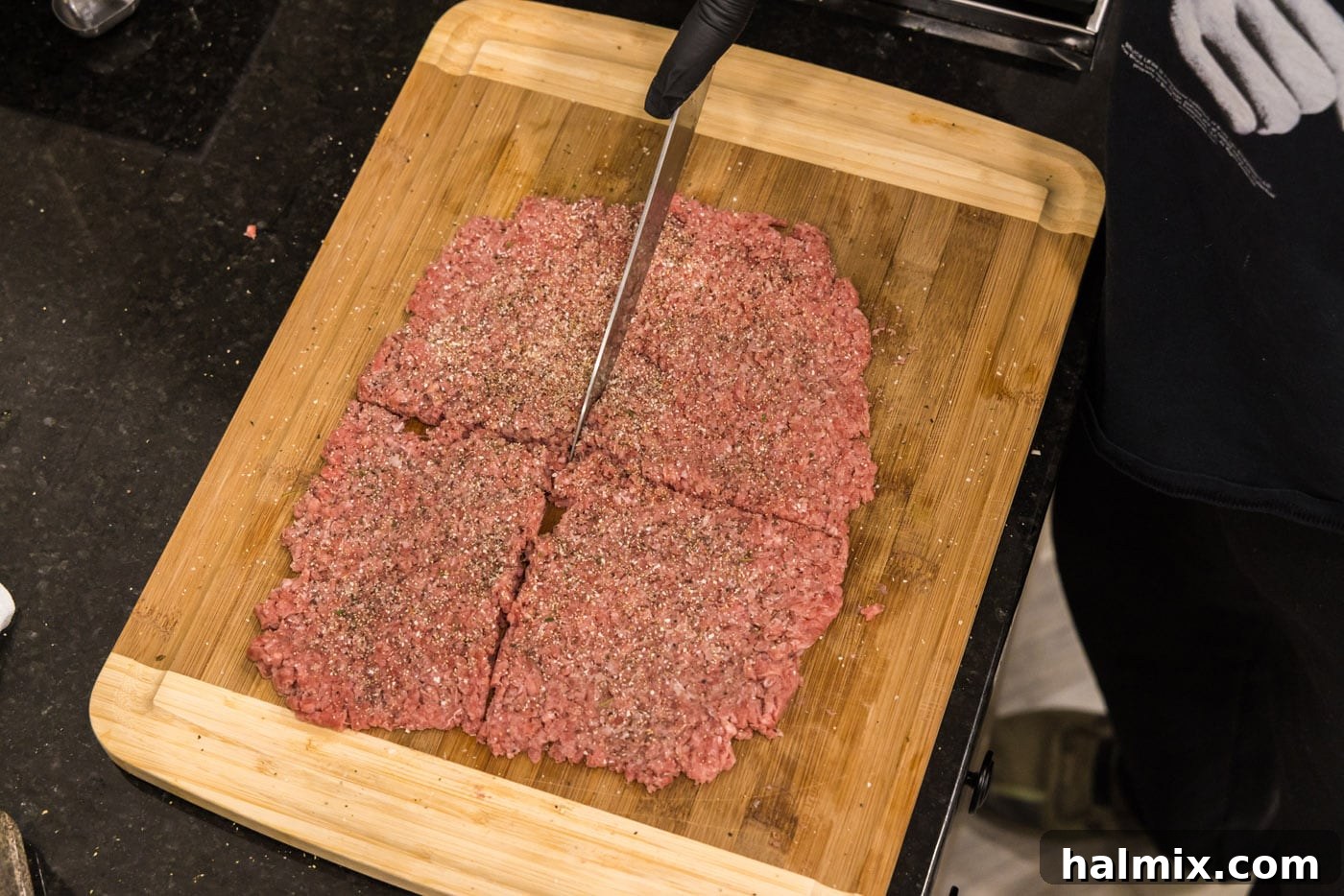Slicing ground beef into four equal sections on a cutting board