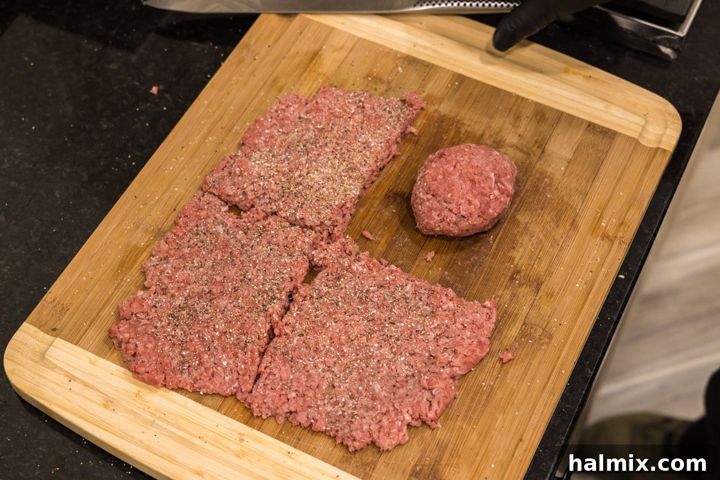 Rolling burger meat into a loose ball on a cutting board