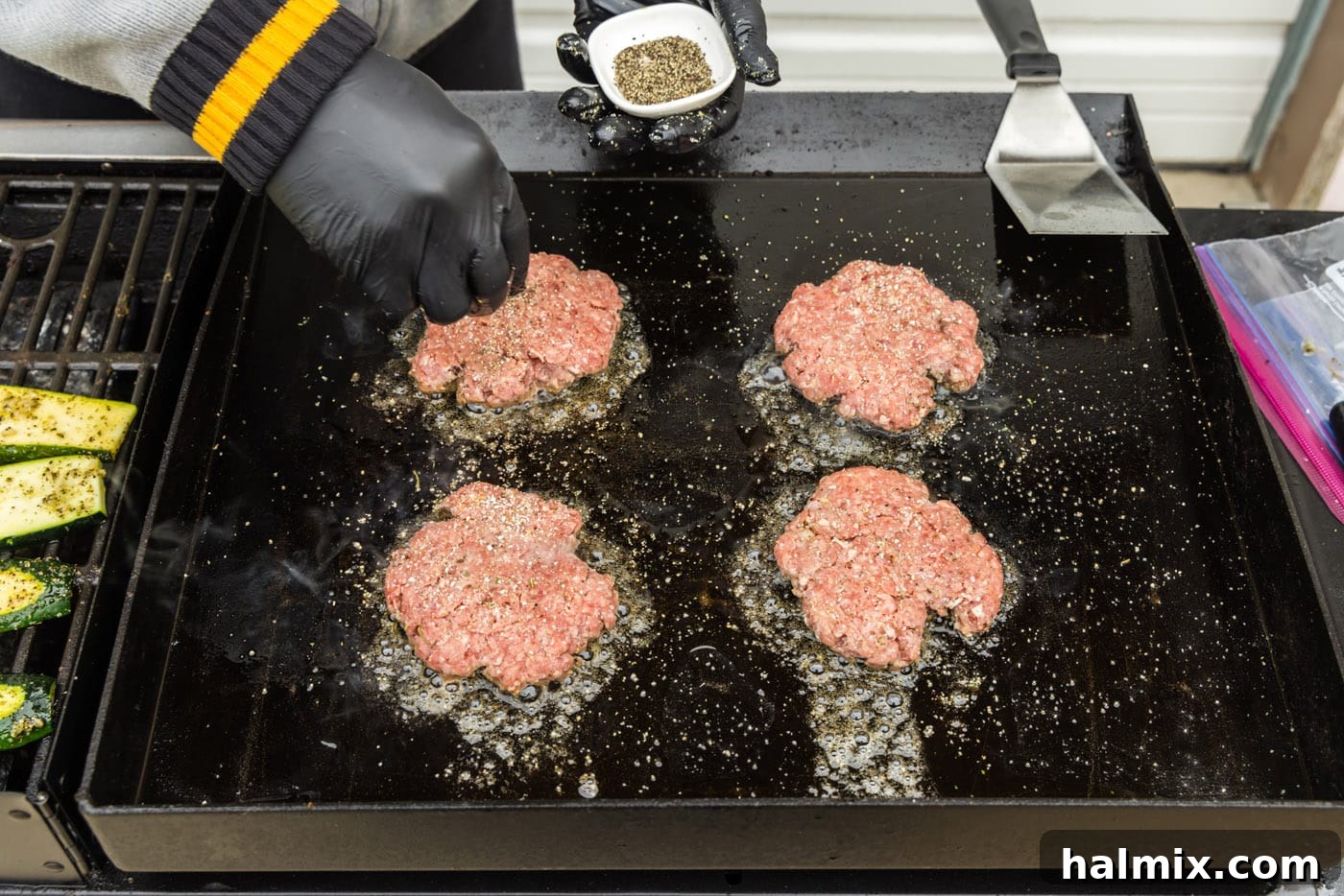 Sprinkling additional seasonings on top of burger patties while cooking