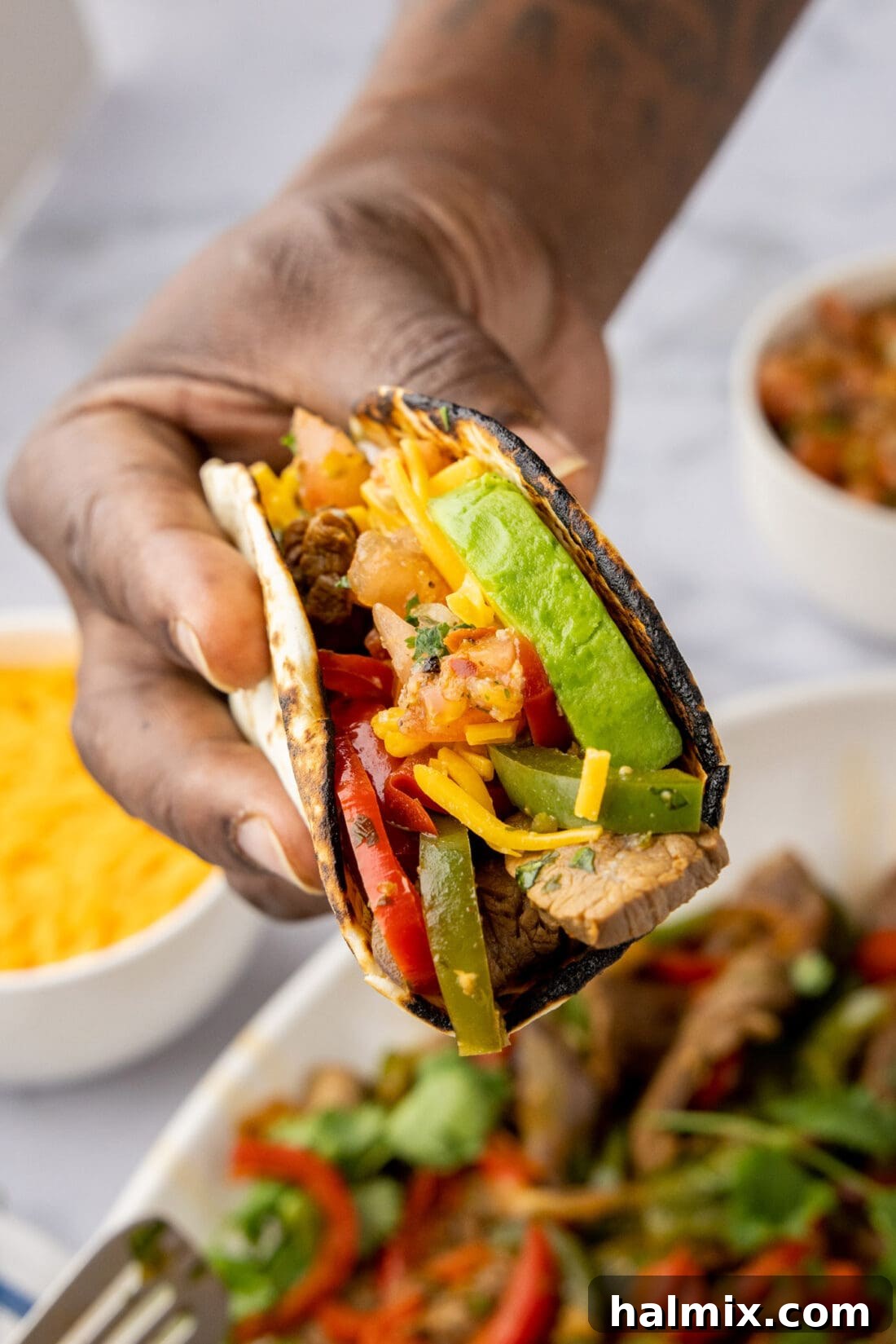 Hand holding Steak Fajitas wrapped in a tortilla 